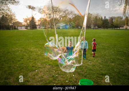 Drei Kinder spielen mit Riesenseifenblasen Stockfoto