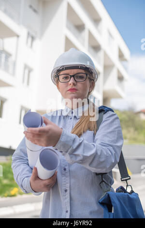 Porträt eines Ingenieurs vor Gebäude, Baupläne Stockfoto