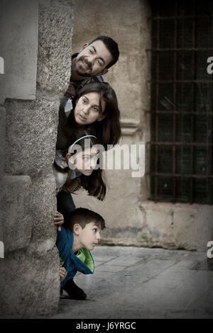 Familie spähte um die Ecke eines Gebäudes Stockfoto