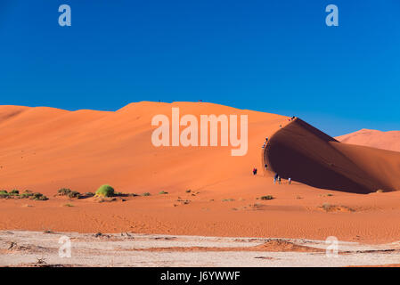 Touristen Klettern malerischen Dünen im Sossusvlei, Namib-Naukluft-Nationalpark, beste touristische und Attraktion in Namibia zu reisen. Abenteuer und expl Stockfoto