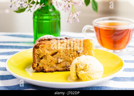Stück vom süßen hausgemachten Apfelkuchen mit Eis und eine Tasse Tee serviert Stockfoto