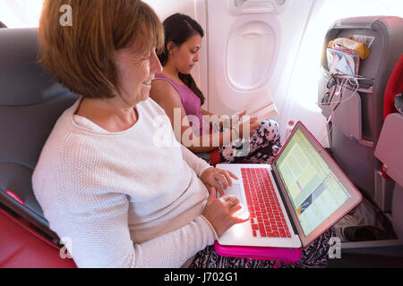 Flugzeug-Passagiere in der Flugzeugkabine mit Laptop-Computer und Pad oder Tablet-Computern; im Flug Stockfoto