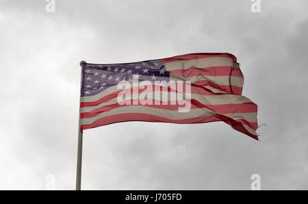 Verblasst und zerfetzt amerikanische Flagge winken gegen ein bewölkter Himmel Stockfoto