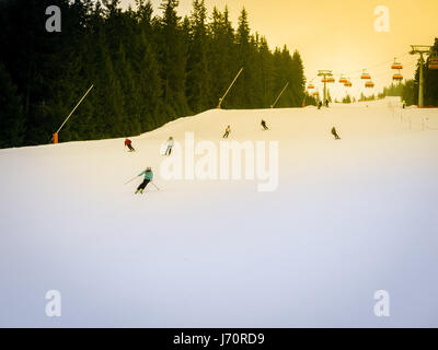 Skifahrer und Snowboarder auf einer Skipiste in Jasna Chopok in Slowakei Skigebiet fahren. Stockfoto