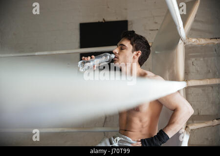 Junge Sportler sitzen in den Boxring und Trinkwasser aus der Flasche Stockfoto