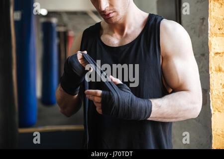 Bild des starken Mannes trägt schwarze Handschuhe für den Boxsport in Turnhalle beschnitten Stockfoto