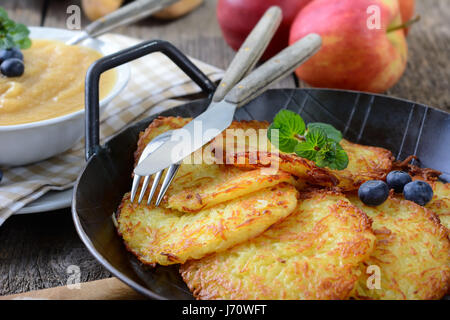 Hausgemachte knusprig gebratene Kartoffelpuffer serviert in einer eisernen Pfanne mit Apfelmus Stockfoto