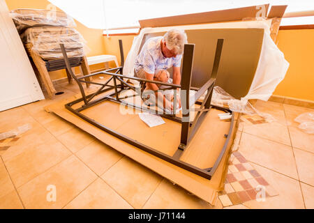 Mann mittleren Alters, Montage flach verpackt Tisch auf der Terrasse Stockfoto