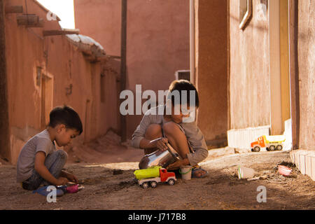 Brüder spielen vor der Tür bei Sonnenuntergang, Abyāneh, Iran Stockfoto