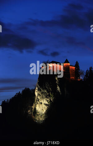 Die mittelalterliche Burg von Bled thront auf einem Felsen über dem See in der Nacht, Slowenien. Stockfoto