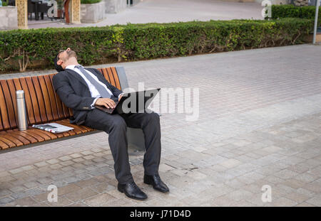 Geschäftsmann gefallen eingeschlafen Onn einer Bank in Dubai Marina, Vereinigte Arabische Emirate Stockfoto