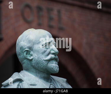 Rüsselsheim, Deutschland. 22. Mai 2017. Eine Bronzestatue des Unternehmens Gründer Adam Opel außerhalb der historischen Opel Eingangsportal im Zentrum von Rüsselsheim, Deutschland, 22. Mai 2017. Der Konzeptkünstler Ottmar Hoerl will eine neue Gruppe von Skulpturen auf dem Platz vor dem Bahnhof, im Auftrag der Stadt Wohnungsbaugesellschaft einrichten. Die Stadt und Denkmal Naturschützer dagegen, da die Statue von Adam Opel und einem historischen Gebäude des Auto-Herstellers sind in unmittelbarer Nähe. Foto: Andreas Arnold/Dpa/Alamy Live-Nachrichten Stockfoto