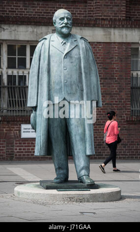 Rüsselsheim, Deutschland. 22. Mai 2017. Eine Bronzestatue des Unternehmens Gründer Adam Opel außerhalb der historischen Opel Eingangsportal im Zentrum von Rüsselsheim, Deutschland, 22. Mai 2017. Der Konzeptkünstler Ottmar Hoerl will eine neue Gruppe von Skulpturen auf dem Platz vor dem Bahnhof, im Auftrag der Stadt Wohnungsbaugesellschaft einrichten. Die Stadt und Denkmal Naturschützer dagegen, da die Statue von Adam Opel und einem historischen Gebäude des Auto-Herstellers sind in unmittelbarer Nähe. Foto: Andreas Arnold/Dpa/Alamy Live-Nachrichten Stockfoto