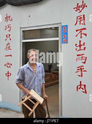 (170523)--JINAN, 23. Mai 2017 (Xinhua)--Zhao Shuhuan hält eine Holzbank Probe in seiner Werkstatt in der Dongtai Dorf der Zhutai Township in Zibo, Ost-China Shandong Provinz, 22. Mai 2017. 54-j hrige Zhao hat Bein Behinderung seit seiner Kindheit hatte. Als er Elder und die Reduzierung der Nachfrage für Zimmerei wuchs, brachte sich Zhao Armut. Vor zwei Jahren half lokale Armutslinderung Abteilung Zhao, eine Werkstatt zu bauen und zu schneiden und polierende Maschinen als eine gezielte Maßnahme in Armutslinderung Kampagnen kaufen. Es fand auch einen Stand auf einem Möbelmarkt für ihn. Umsatzvolumen von Stockfoto