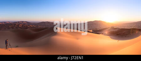 Fotografen auf Sanddünen in der Wüste bei Sonnenaufgang in der Nähe von Merzouga, Marokko Stockfoto