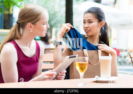 Zwei junge Frauen diskutieren eine Kleidung kaufen Stockfoto