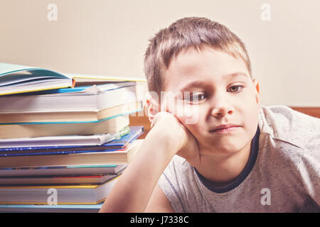 Gelangweilt Kind zwischen Haufen Bücher Stockfoto