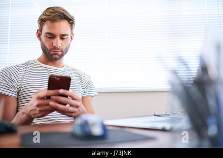 Erwachsene kaukasischen Mann beschäftigt Tippen auf seinem Handy im sitzen Stockfoto