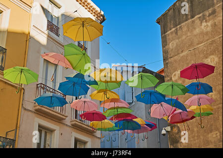 Bunte Schirme hängen zwischen den Gebäuden oberhalb einer Straße in der Altstadt von Beziers, Frankreich Stockfoto