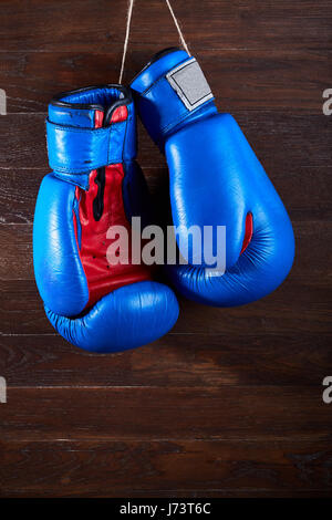 Blaue und rote Boxhandschuhe an Holzwand hängen. Stockfoto