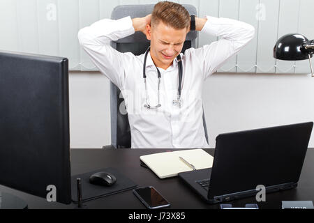 Foto von einem stressigen jungen männlichen Arzt in seinem medizinischen Büro Stockfoto