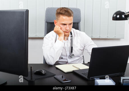 Foto von einem müden jungen männlichen Arzt in seinem medizinischen Büro Stockfoto