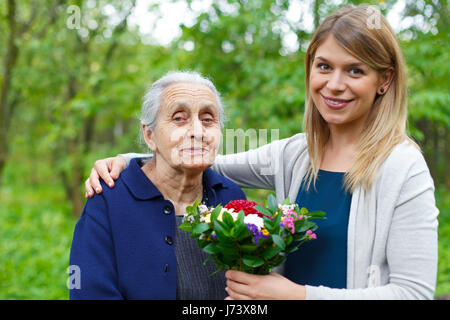 Porträt einer gerne ältere Frau, die Blumen von ihrer Enkelin Stockfoto