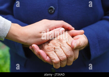 Nahaufnahme der Hände ist eine ältere Frau mit ihrem Enkelkind Stockfoto