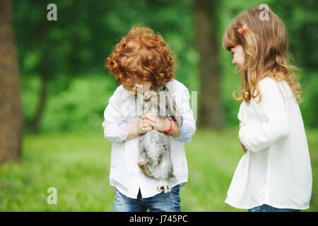 kleine Jungen und Mädchen spielen mit Kaninchen Stockfoto