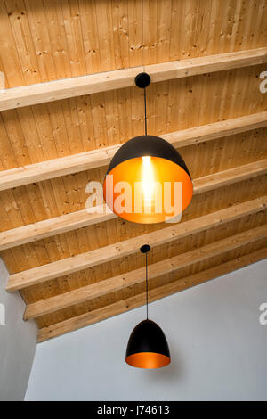 moderne Leuchten hängen von einer Holzdecke Stockfoto