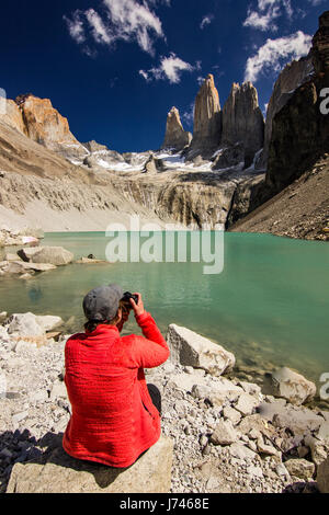 Mädchen im roten Jacke sitzt in der Nähe von blauen See in Patagonien, Foto mit Kamera Stockfoto