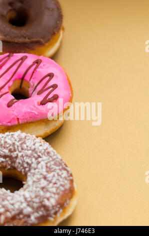 Nahaufnahme von einem sortierten leckere Donuts mit rosa, Schokolade, Kokos, Erdnuss verglaste untergebrachte in einer Linie über einem hölzernen Hintergrund Stockfoto