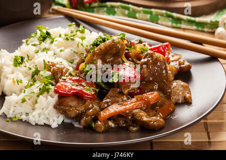 Chinesische klebrige Schweinefleisch Rinderfilet gebraten mit einem süßen und herzhaften Soße mit gekochtem Reis serviert Stockfoto