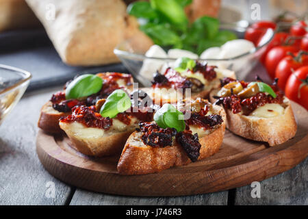 Vorspeise-Bruschetta mit getrockneten Tomaten, Oliven und Mozarella. Italienische Küche Stockfoto