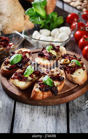 Vorspeise-Bruschetta mit getrockneten Tomaten, Oliven und Mozarella. Italienische Küche. Ansicht von oben Stockfoto