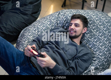 Gamer mit Videospielen mit Joystick sitzt auf Bohnenbeutelstuhl Stockfoto