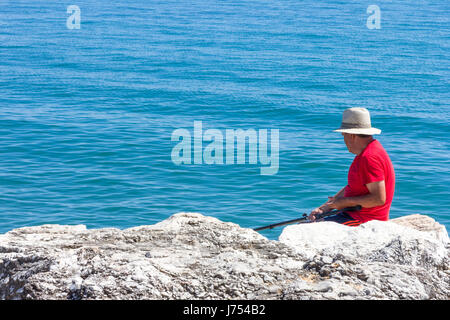 Mann Angeln vom Felsen Strand Torremolinos, Spanien Stockfoto