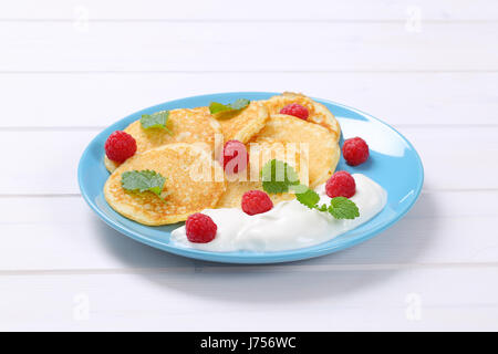 Teller mit amerikanische Pfannkuchen mit Joghurt und frischen Himbeeren auf weißem Holz Hintergrund Stockfoto