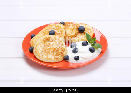 Teller mit amerikanische Pfannkuchen mit Joghurt und frische Heidelbeeren auf weißem Holz Hintergrund Stockfoto