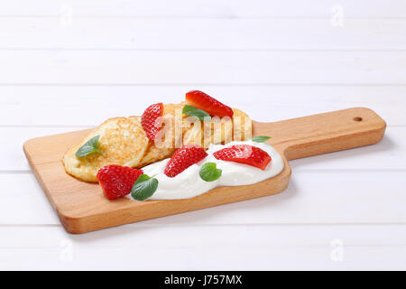 amerikanische Pfannkuchen mit Joghurt und frischen Erdbeeren auf Holzbrett Stockfoto