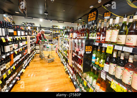 Kunden mit einem Einkaufswagen betrachten Reihen von Weinflaschen zum Verkauf an BWS Bottle Shop, Kiama, New-South.Wales, NSW, Australien Stockfoto