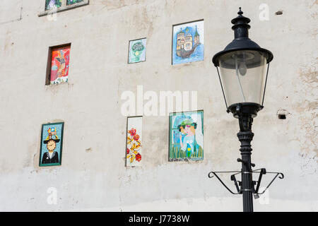 Eine Straßenlaterne mit einer Mauer mit einigen Figuren bemalt im Hintergrund in Bratislava Stockfoto