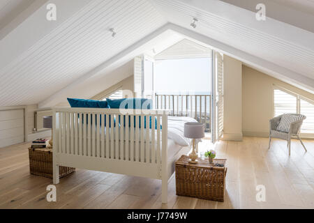 Feder & schwarz Bett im Obergeschoss Schlafzimmer mit schrillen Decke, Balkon und Fensterläden. Geschenkkörbe von Fortnum & Mason wurden als Nachttisch Registerkarte verwendet Stockfoto