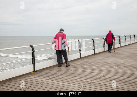 Ein älteres paar Spaziergang entlang der Pier am Saltburn am Meer, England, UK Stockfoto