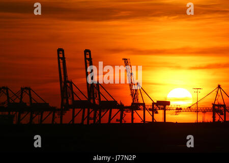 Tilbury, Essex, England. 23. Mai 2017. Die Sonne gesehen hinter dem Kai Krane und Windkraftanlagen von Tilbury Docks aus über die Themse in Gravesend am Abend des 23. Mai einstellen. Rob Powell/Alamy Live-Nachrichten Stockfoto