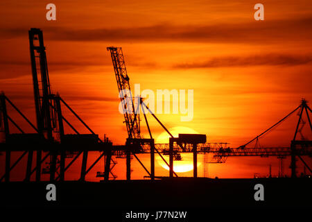 Tilbury, Essex, England. 23. Mai 2017. Die Sonne gesehen hinter dem Kai Krane und Windkraftanlagen von Tilbury Docks aus über die Themse in Gravesend am Abend des 23. Mai einstellen. Rob Powell/Alamy Live-Nachrichten Stockfoto