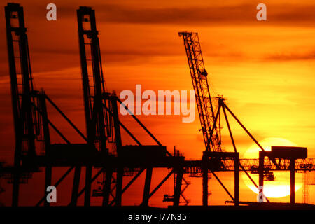 Tilbury, Essex, England. 23. Mai 2017. Die Sonne gesehen hinter dem Kai Krane und Windkraftanlagen von Tilbury Docks aus über die Themse in Gravesend am Abend des 23. Mai einstellen. Rob Powell/Alamy Live-Nachrichten Stockfoto