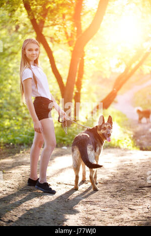 Teenager-Mädchen in weißen Hemd mit ihrem Hund auf Weg im Park sitzend Stockfoto