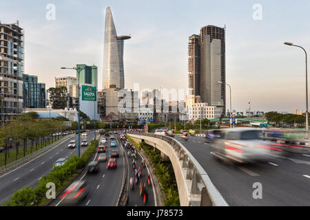 HO-CHI-Minh-Stadt, VIETNAM - 14. April 2017: Verkehr eilt entlang den Autobahnen in Ho-Chi-Minh-Stadt mit der Skyline des Geschäftsviertels in Vietnam Stockfoto
