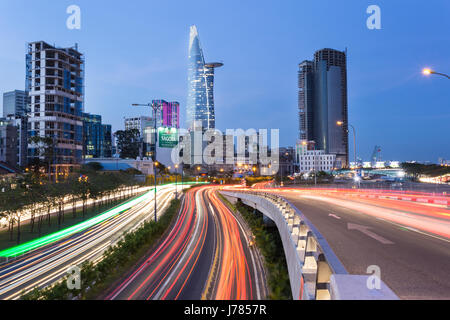 HO-CHI-Minh-Stadt, VIETNAM - 14. April 2017: Verkehr eilt entlang den Autobahnen in Ho-Chi-Minh-Stadt mit der Skyline des Geschäftsviertels in Vietnam Stockfoto
